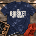 Navy T-shirt with the design “In Brisket We Trust.” printed on the front.