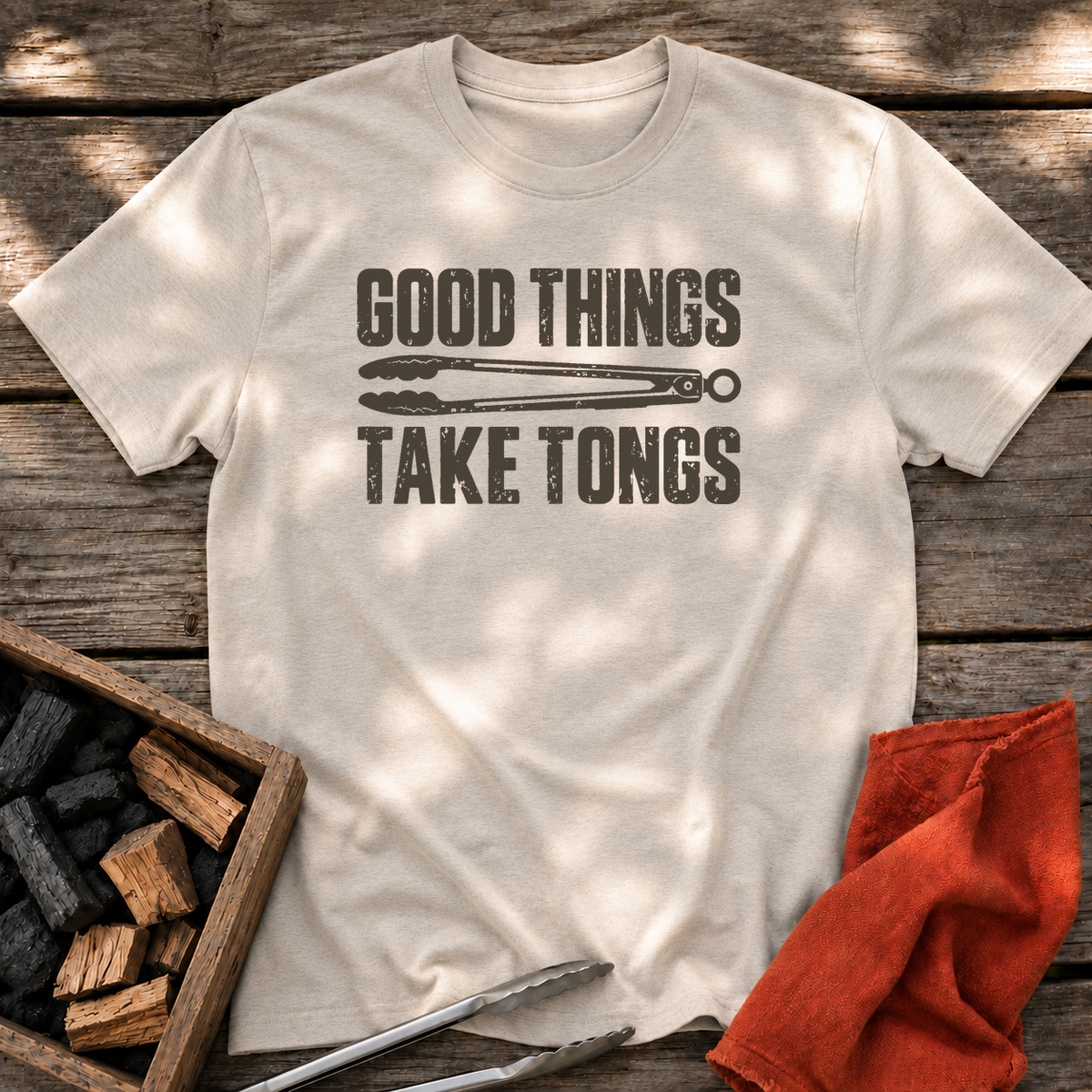 Natural T-shirt with the design “GOOD THINGS TAKE TONGS” printed on the front.