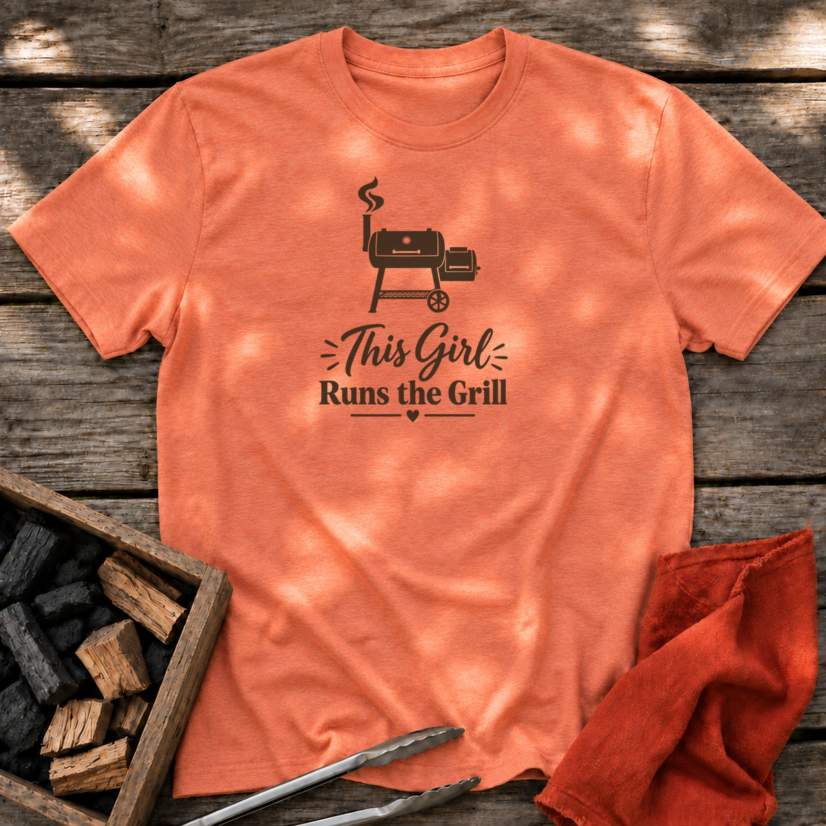 Heather Orange T-shirt with the design “This Girl Runs the Grill” printed on the front.