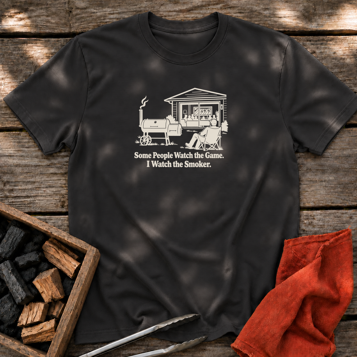 Black T-shirt with the design “Some People Watch the Game. I Watch the Smoker.” printed on the front.