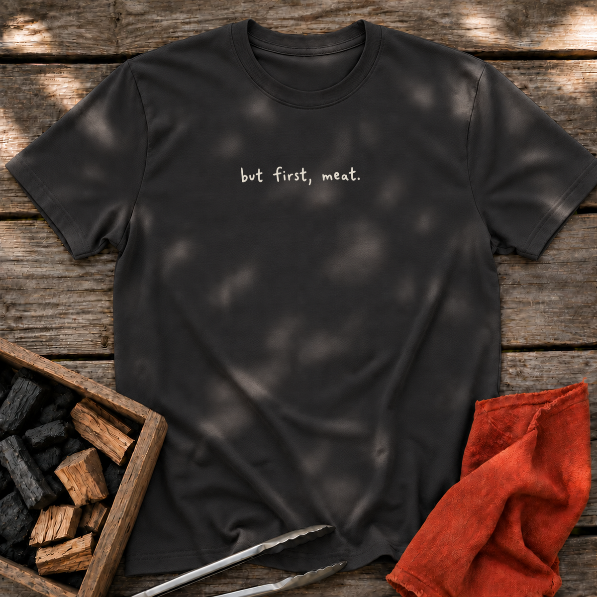 Black T-shirt with the design “but first, meat.” printed on the front.
