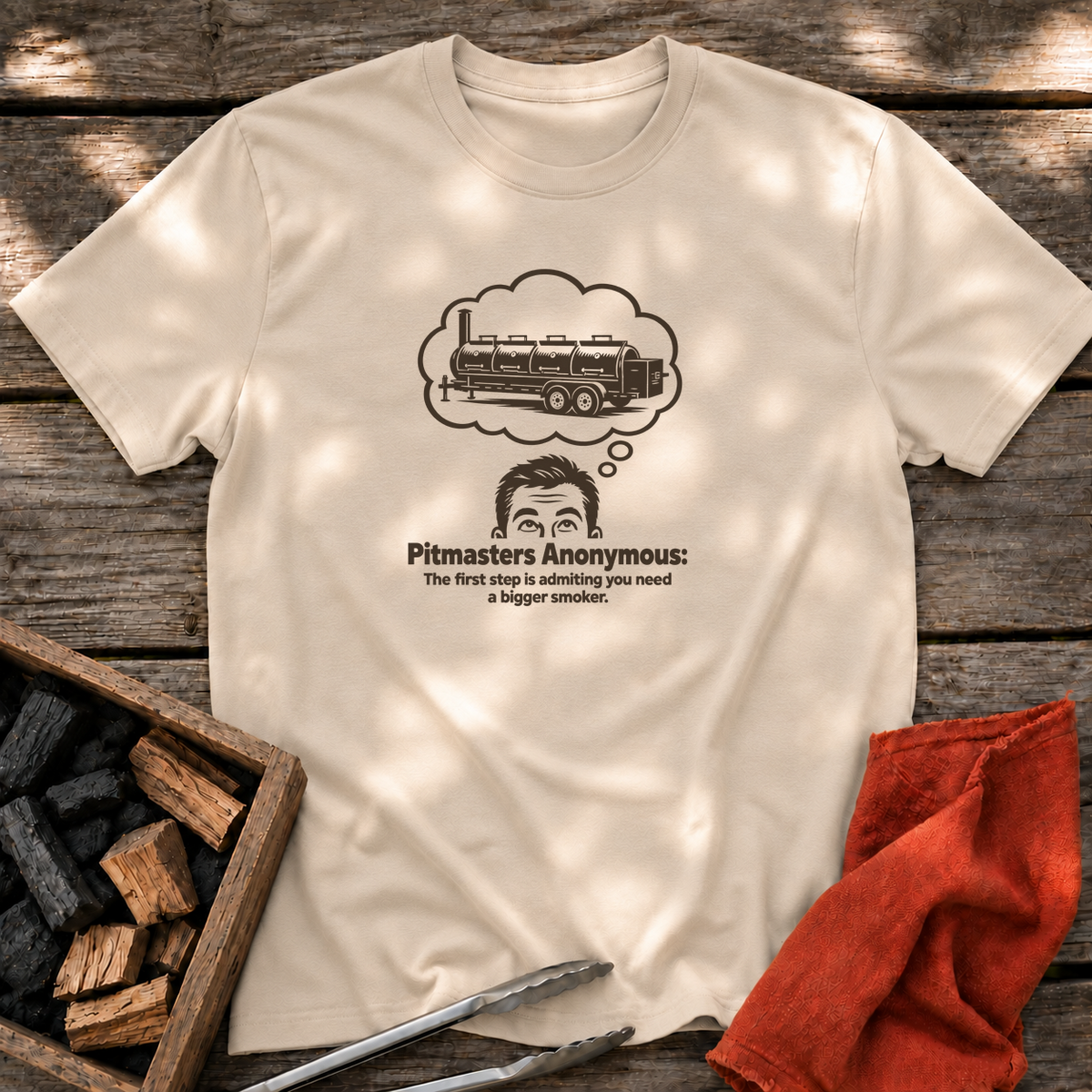 Sand T-shirt with the design “Pitmasters Anonymous: The first step is admitting you need a bigger smoker.” printed on the front.