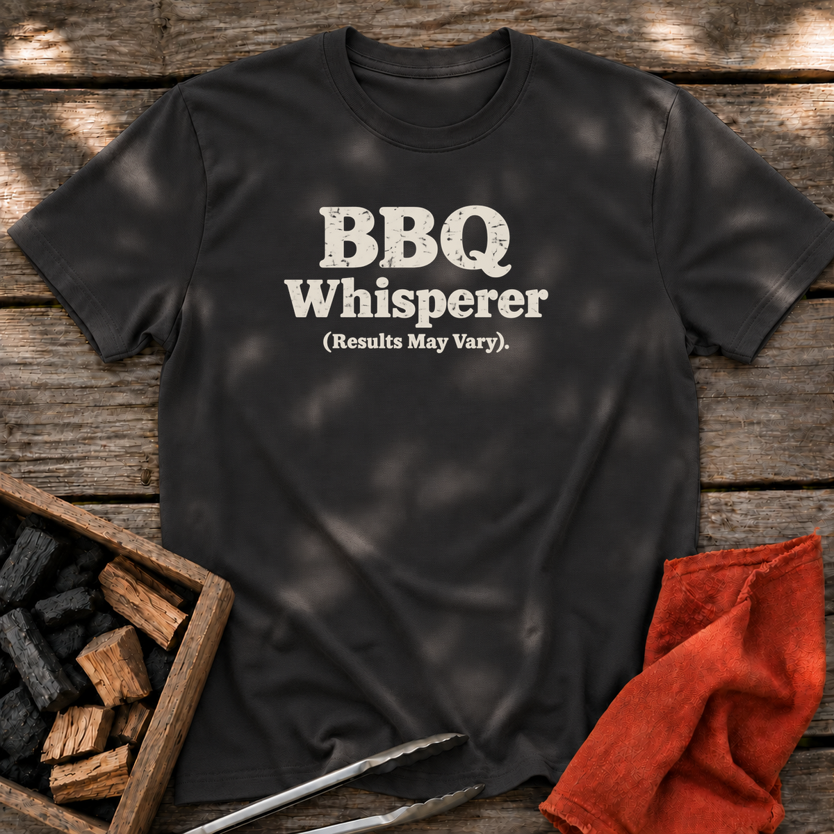 Black T-shirt with the design “BBQ Whisperer (Results May Vary).” printed on the front.