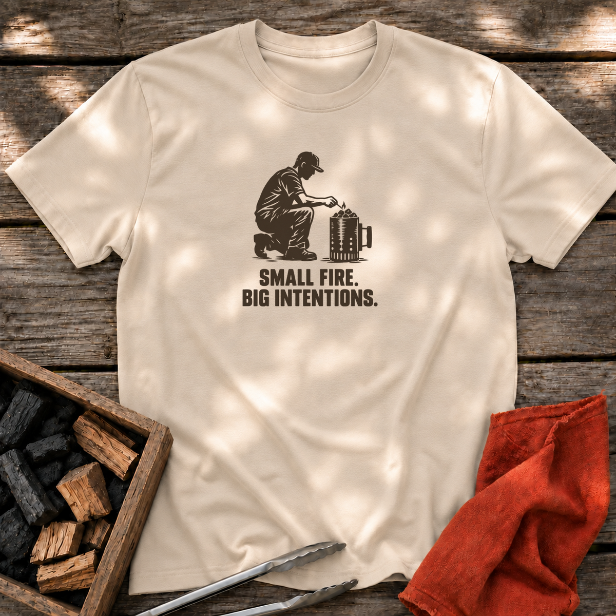 Sand T-shirt with the design “SMALL FIRE. BIG INTENTIONS.” printed on the front.