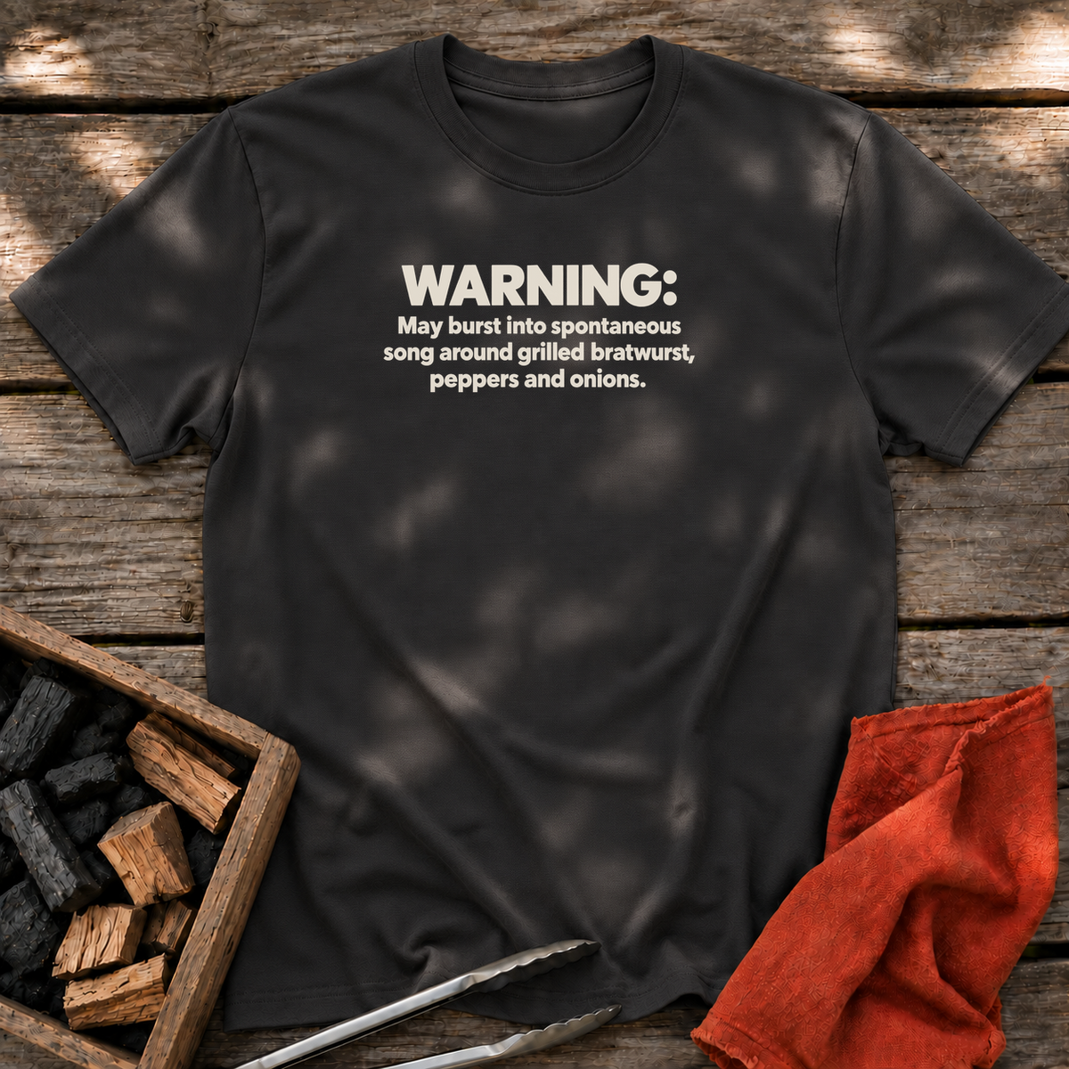 Black T-shirt with the design “WARNING: May burst into spontaneous song around grilled bratwurst, peppers and onions.” printed on the front.