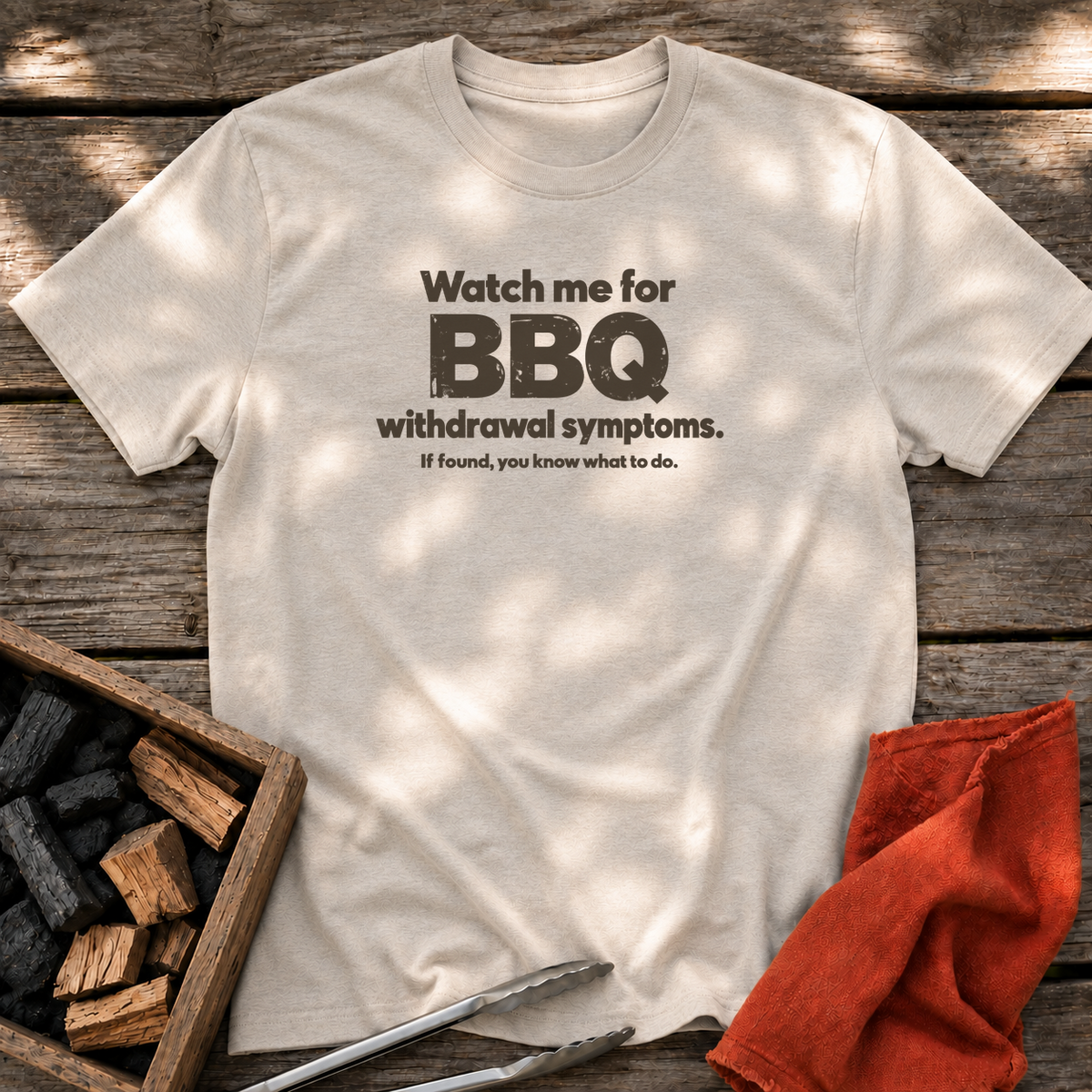 Natural T-shirt with the design “Watch me for BBQ withdrawal symptoms. If found, you know what to do.” printed on the front.