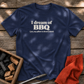 Navy T-shirt with the design “I dream of BBQ (yes, my pillow is drool-soaked)” printed on the front.