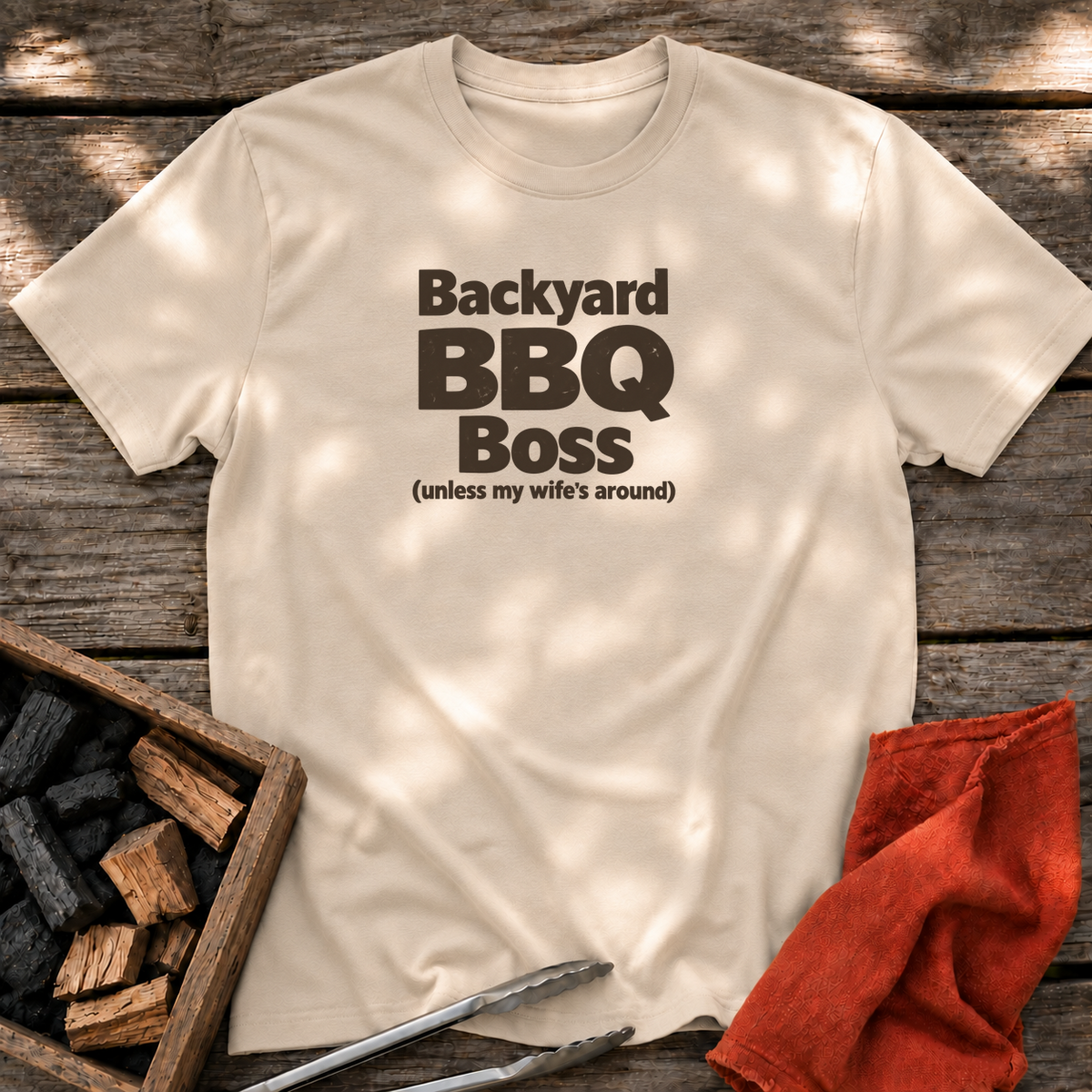 Sand T-shirt with the design “Backyard BBQ Boss (unless my wife's around)” printed on the front.