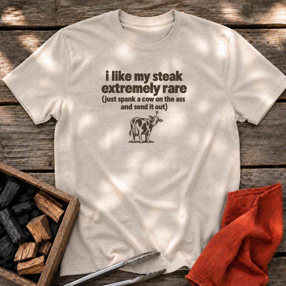 Natural T-shirt with the design “i like my steak extremely rare (just spank a cow on the ass and send it out)” printed on the front.