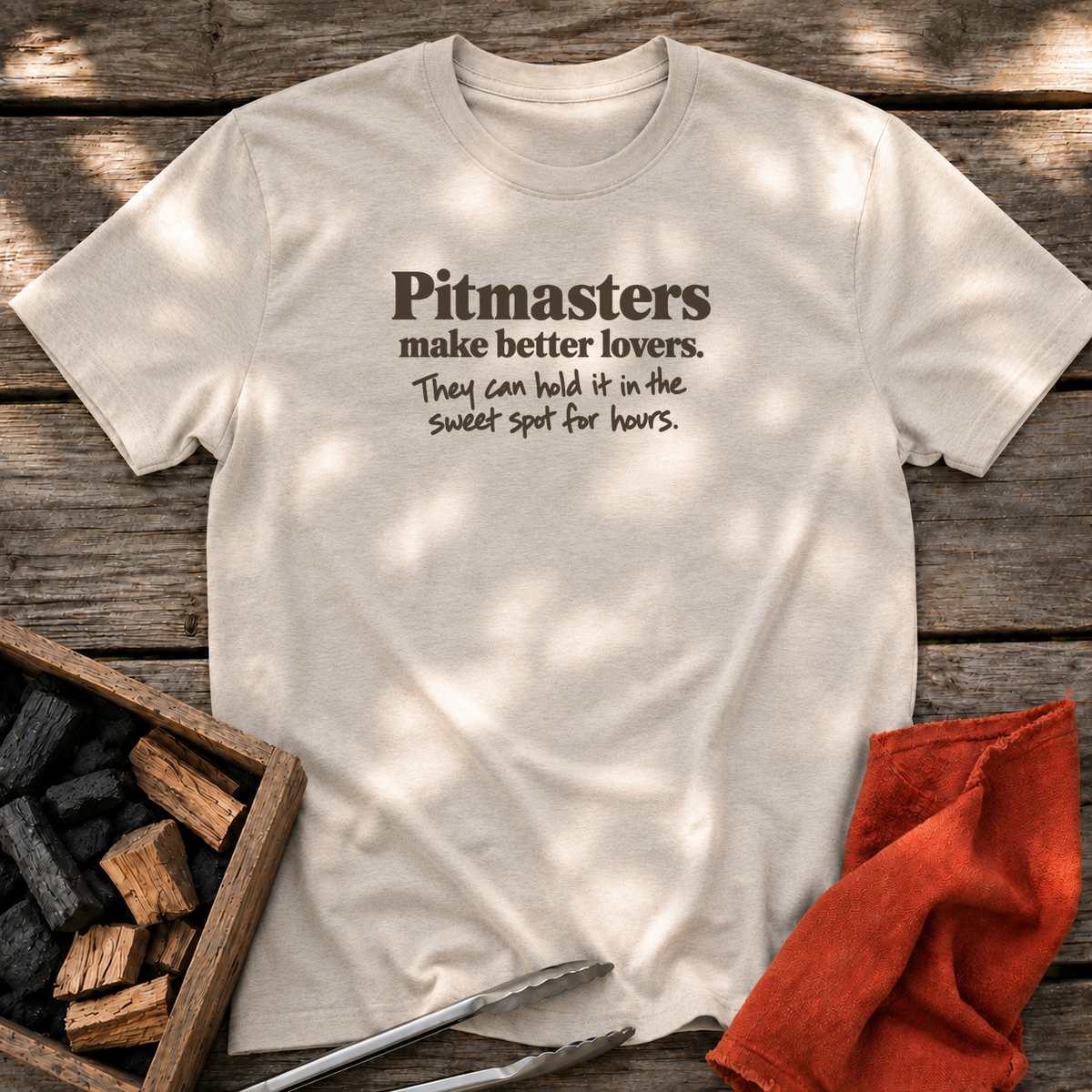 Natural T-shirt with the design “Pitmasters make better lovers. They can hold it in the sweet spot for hours.” printed on the front.