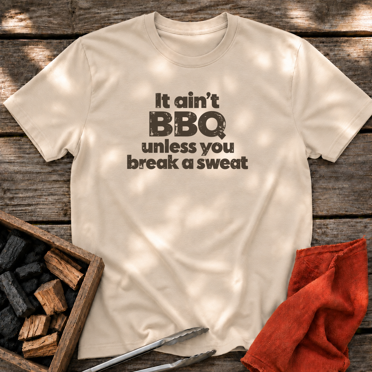 Sand T-shirt with the design “It ain't BBQ unless you break a sweat” printed on the front.