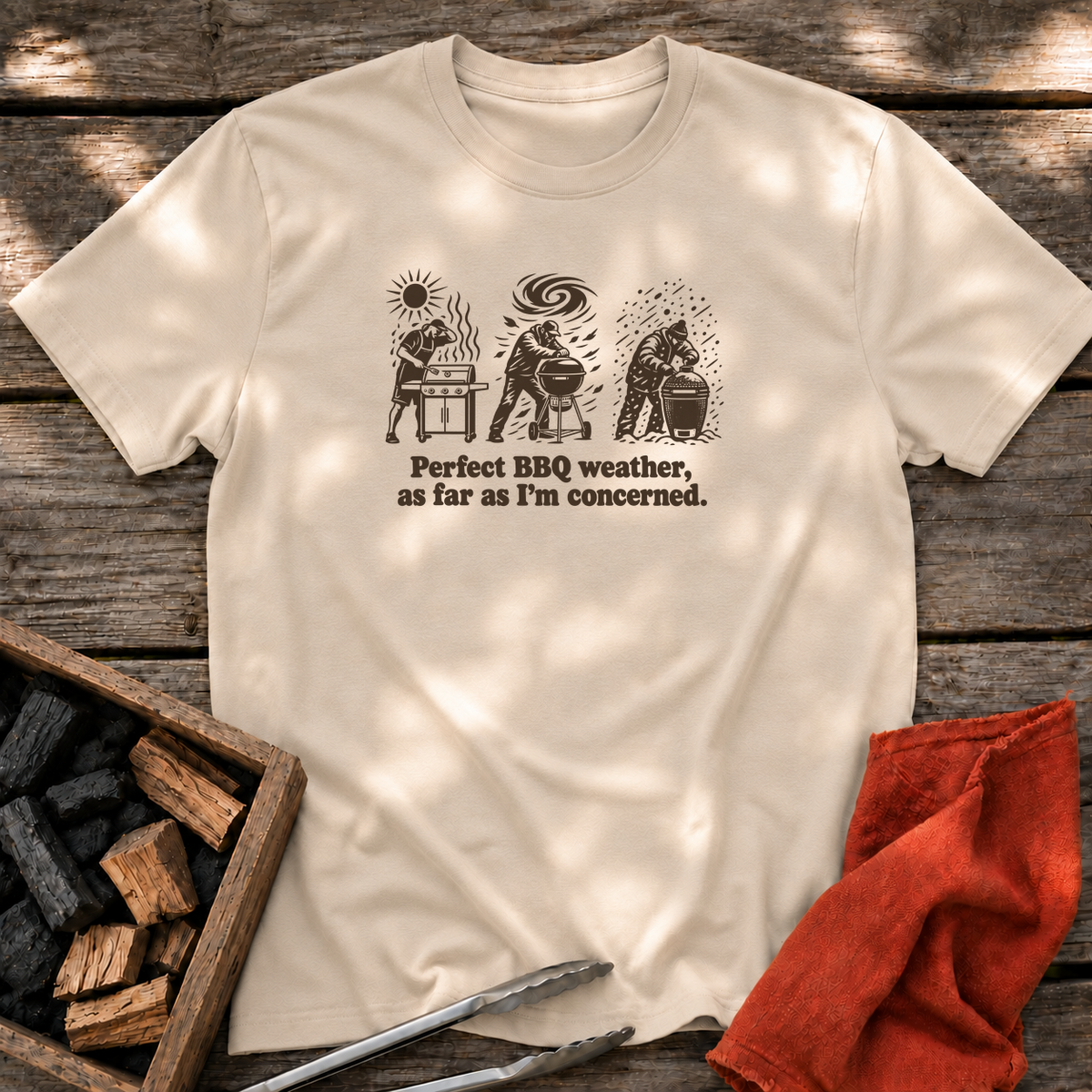 Sand T-shirt with the design “Perfect BBQ weather, as far as I'm concerned.” printed on the front.